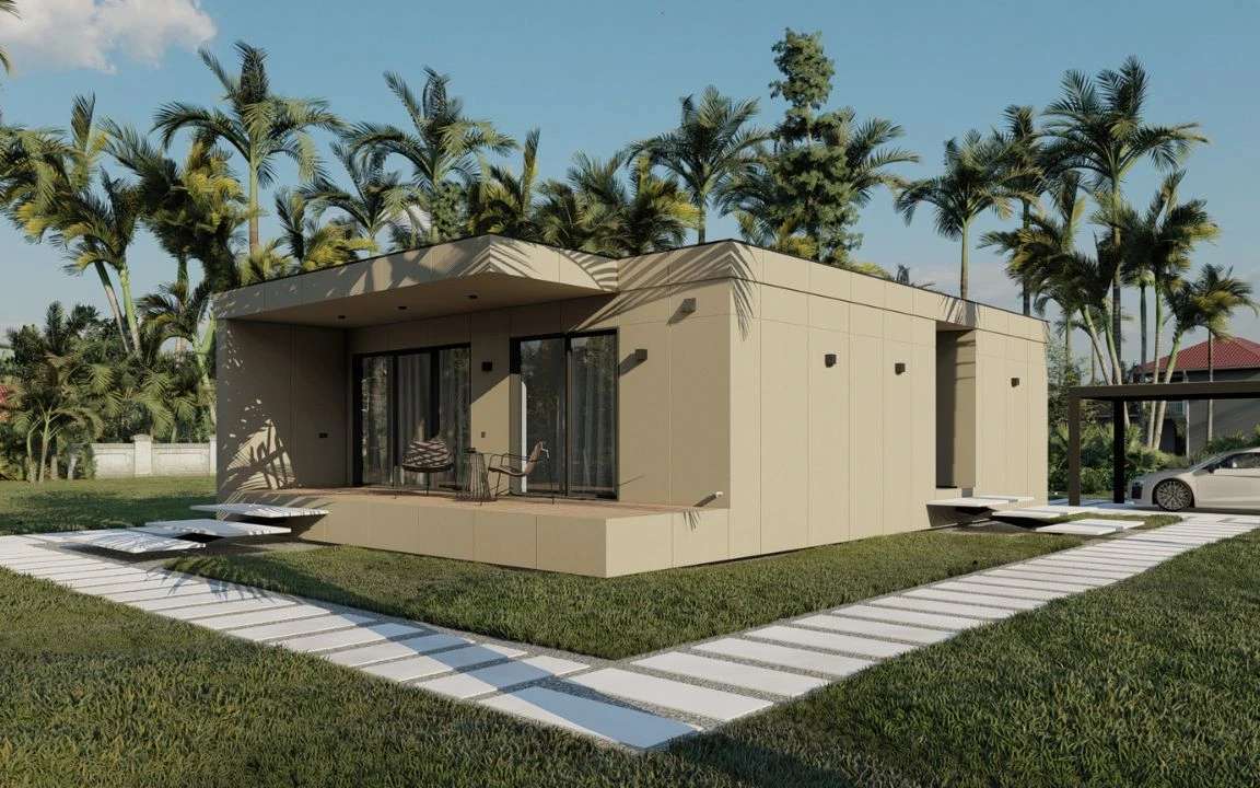 Modern modular home with a beige exterior, featuring a front deck, large sliding glass doors, and a sleek pathway surrounded by palm trees and green lawn.