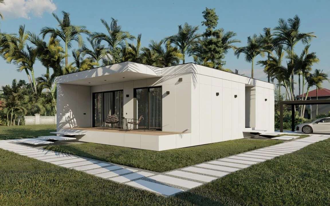 Elegant white modular home with a minimalist design, front porch area, and tropical garden backdrop including palm trees and a parked car in a black-frame carport.