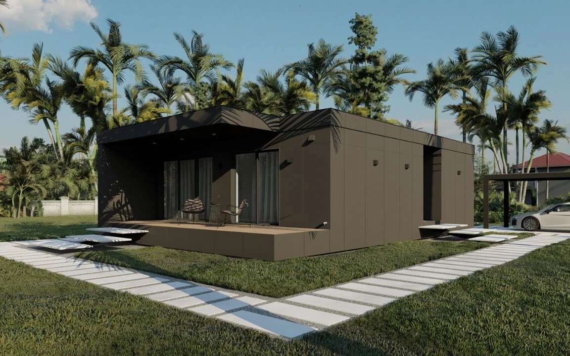 Contemporary two-bedroom modular house in dark brown, showcasing a wooden deck, minimal black lighting fixtures, and tropical landscaping with a carport visible.