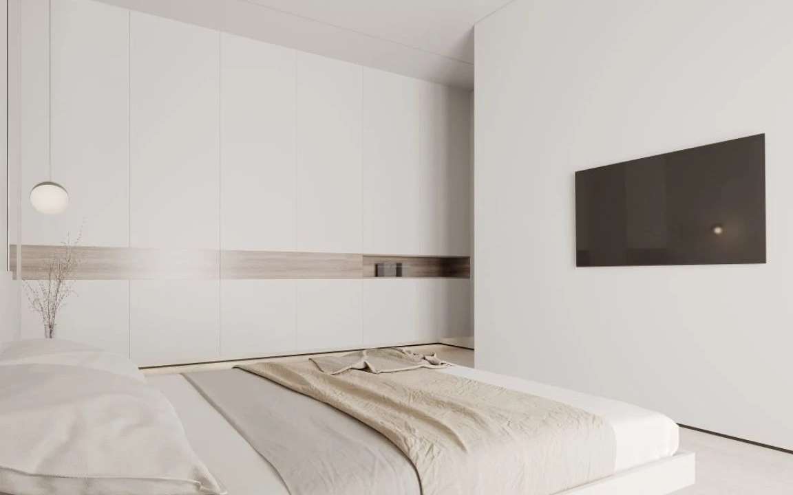 Bedroom with floor-to-ceiling wardrobes and mounted TV opposite bed