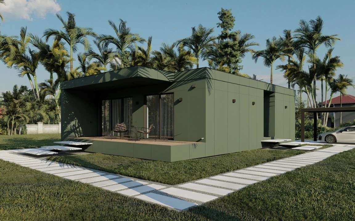 Stylish prefabricated home with a green facade, front-facing patio, and a clean grid-like path, set in a tropical garden with tall palm trees.