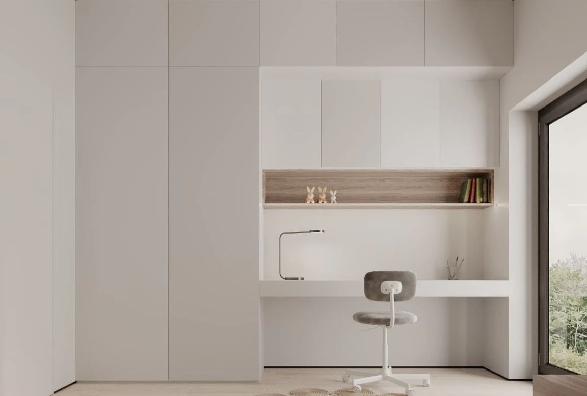 Minimalist study nook with built-in desk, overhead cabinets, and natural lighting